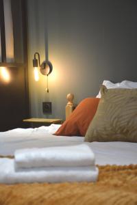 um quarto com uma cama com lençóis brancos e um candeeiro em Domaine des cyprès em Vaudrimesnil