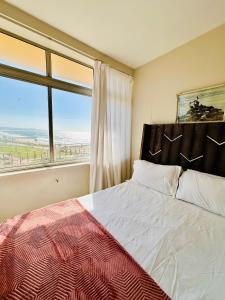 a bedroom with a bed and a large window at Nomacurvy beach front accommodation in Durban