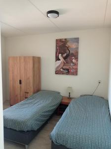 een slaapkamer met 2 bedden en een schilderij aan de muur bij Appartement IJsselmeer Makkum strand in Makkum