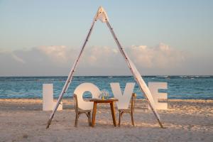ein Tisch und Stühle am Strand mit dem Wort Liebe in der Unterkunft The Westin Puntacana Resort in Punta Cana