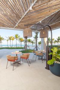 an outdoor patio with tables and chairs and the ocean at The Westin Puntacana Resort in Punta Cana