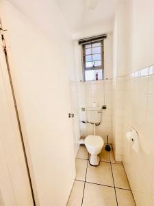 a bathroom with a toilet and a window at Nomacurvy beach front accommodation in Durban