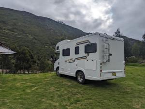 a white rv parked in a field with a mountain at Casa Rodante amplia en Cusco in Cusco
