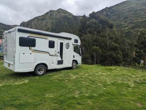 a white trailer parked in a field with a mountain at Casa Rodante amplia en Cusco in Cusco