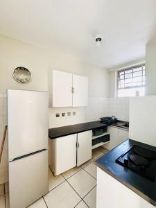 cocina con armarios blancos y encimera negra en Nomacurvy beach front accommodation en Durban