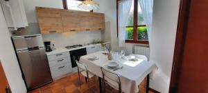 Il comprend une cuisine équipée d'une table blanche avec des chaises et d'un réfrigérateur. dans l'établissement Elisa Holidays Apartments, à Puegnago
