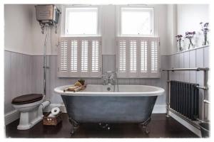 uma casa de banho com uma banheira, um WC e janelas em Family House with Garden & Sea Views em Mousehole
