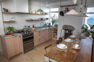 uma cozinha com uma mesa, um lavatório e um fogão em Family House with Garden & Sea Views em Mousehole