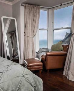 um quarto com um espelho, um sofá e uma cadeira em Family House with Garden & Sea Views em Mousehole