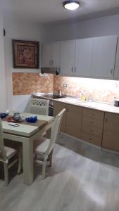 eine Küche mit weißen Schränken sowie einem Tisch und Stühlen in der Unterkunft Fjori's Apartment in Korçë