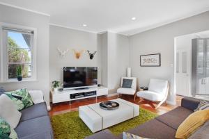 a living room with a couch and a tv at Prosper Point Home with BBQ, Patio and Parking in Auckland
