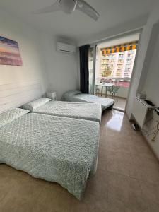 a bedroom with three beds and a balcony at Tamarindo 5 in Benalmádena