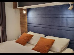 a bed with two pillows and a blue headboard at Mobile home JOY in Biograd na Moru