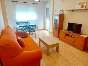 a living room with an orange couch and a table at Apartamento El Ingenio con balcón y aparcamiento en Almería - Alborania in Almería