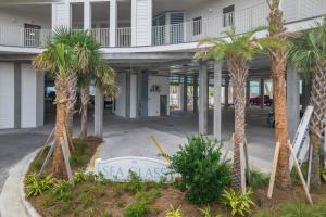 a sign in front of a building with palm trees at Sea Glass 316 by Vacation Homes Collection in Gulf Shores