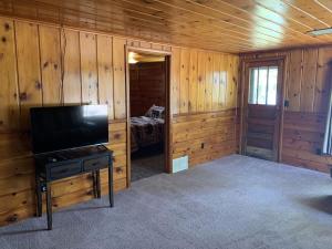 uma sala de estar com uma televisão de ecrã plano num chalé de madeira em Gresham Shores-Hungry Bear em Arbor Vitae