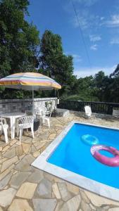 - une piscine avec une table et un parasol dans l'établissement Casa para relaxar, estilosa e privativa, à Nazaré Paulista