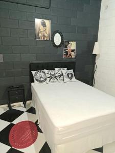 ein weißes Bett in einem Zimmer mit einer Uhr an der Wand in der Unterkunft Casa para relaxar, estilosa, privativa e pet friendly in Nazaré Paulista