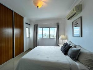 a bedroom with a large white bed with a window at Private beach front Apartment in Juan Dolio in Los Corrales