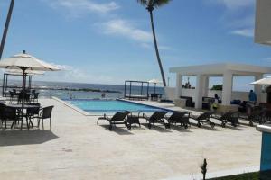 a pool with chairs and a table and an umbrella at Private beach front Apartment in Juan Dolio in Los Corrales