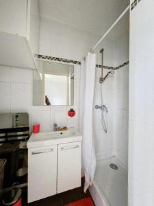 ein weißes Bad mit einer Dusche und einem Waschbecken in der Unterkunft Studio avec jardin a Corbeil-Essonne in Corbeil-Essonnes
