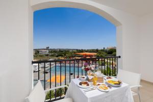 Regency Salgados Hotel & Spa في ألبوفيرا: طاولة طعام وإطلالة على المسبح