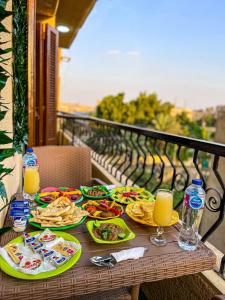 una mesa con platos de comida y bebida en el balcón en Tapiri pyramids inn, en El Cairo