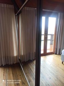 um quarto com uma porta de vidro e um quarto com pisos de madeira em Chalé Santos em Jaguaruna
