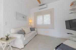 a white living room with a white couch and a tv at Chalet independiente a 50 metros de Cala Blanca in Jávea