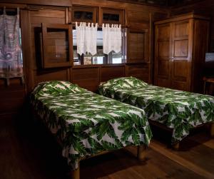 Mariuti的住宿－LE ROCHER DE TAHITI，客房设有两张带绿盖的床和窗户。