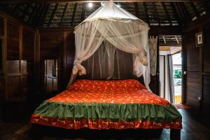 ein Schlafzimmer mit einem Himmelbett in der Unterkunft LE ROCHER DE TAHITI in Mariuti