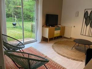 een woonkamer met een televisie en een tafel en stoelen bij logement avec accès piscine in Chaumont-sur-Tharonne