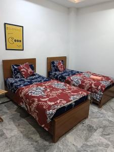 dos camas sentadas una al lado de la otra en una habitación en Dastak Hotel, en Islamabad