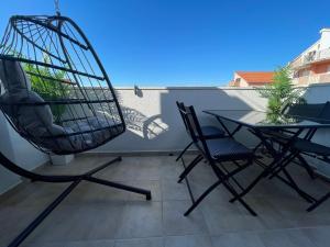 a balcony with a table and chairs and a bird cage at Apartment New Chic in Supetar +37 photos