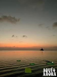 a sunset over the water with a boat in the distance at Aqui Ahora at Villa Verde in San Andrés