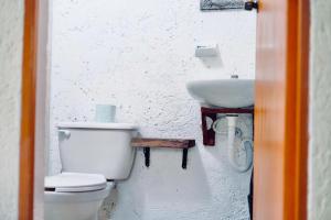 een witte badkamer met een toilet en een wastafel bij Hostel Utopia in Holbox Island