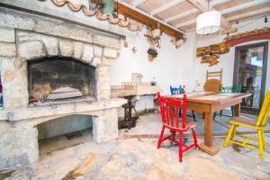 a stone fireplace in a living room with a wooden table and chairs at Apartment Sanja in Pirovac