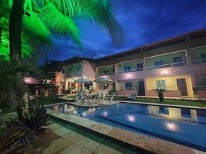 a villa with a swimming pool at night at Pousada Porto das Dunas in Aquiraz