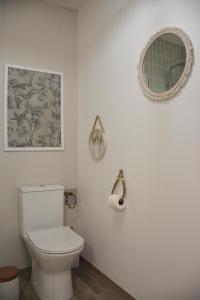 ein weißes Bad mit einem WC und einem Spiegel in der Unterkunft Domaine des cyprès in Vaudrimesnil