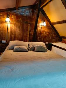 uma cama grande com duas almofadas num quarto em Cabaña en la Calera BersaNina em La Calera