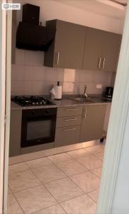 a kitchen with gray cabinets and a sink and a stove at Bel appartement in Zarzis