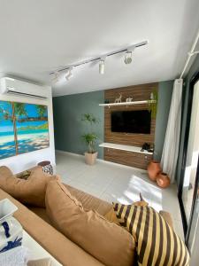 a living room with a couch and a flat screen tv at Refúgio na Praia do Forte in Praia do Forte