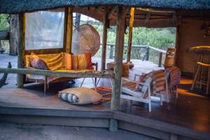a porch of a house with chairs and a fan at Hyenas Howl Cabins & Campground in Muchenje