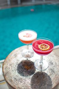 zwei Cocktails auf einem Holztisch neben einem Pool in der Unterkunft Virgin Hotels New Orleans in New Orleans