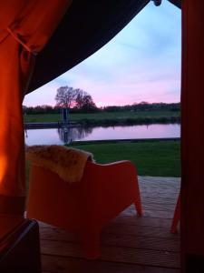 a person standing on a porch looking out at a lake at Safari Lodge Aan de Linge in Tiel