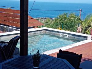 a swimming pool with a table and a view of the ocean at La Villa Choka in Trois Bassins
