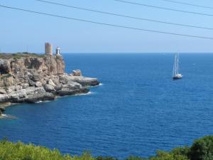 un voilier dans l'eau à côté d'une côte rocheuse dans l'établissement Hotel Rocamar, à Cala Figuera