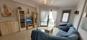 a living room with a blue couch and a tv at Paralia Ofriniou Sea view apartment in Orfánion