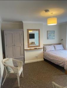 a bedroom with a bed and a chair and a mirror at Fernlea Guest house in Weston-super-Mare