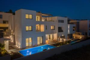 - un grand bâtiment blanc avec une piscine la nuit dans l'établissement Villa Toma, à Podstrana